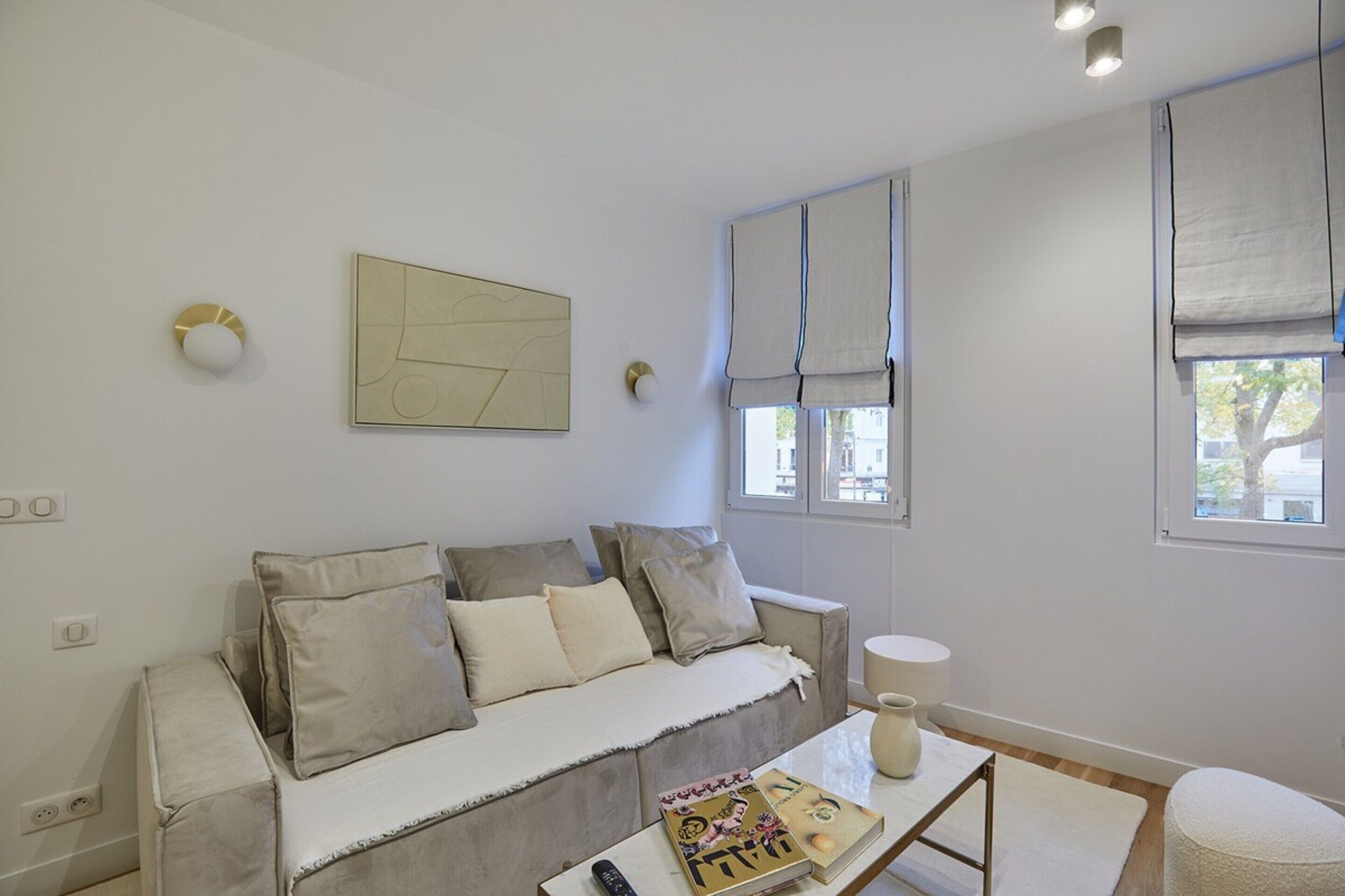 Un salon moderne avec un canapé, une table basse et une fenêtre avec des rideaux.