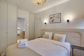 Een keurig opgemaakt slaapkamer met een groot bed, een nachtkastje, een kledingkast en een lijst met kunstwerk aan de muur.