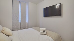 Une chambre d’hôtel avec un lit, un téléviseur à écran plat fixé au mur et une fenêtre avec des stores.
