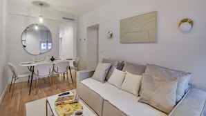 Un salon moderne comprenant un coin repas, un canapé et un miroir rond.