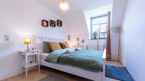 Une chambre à coucher avec un lit, une table de chevet, une lampe et une fenêtre avec des rideaux.