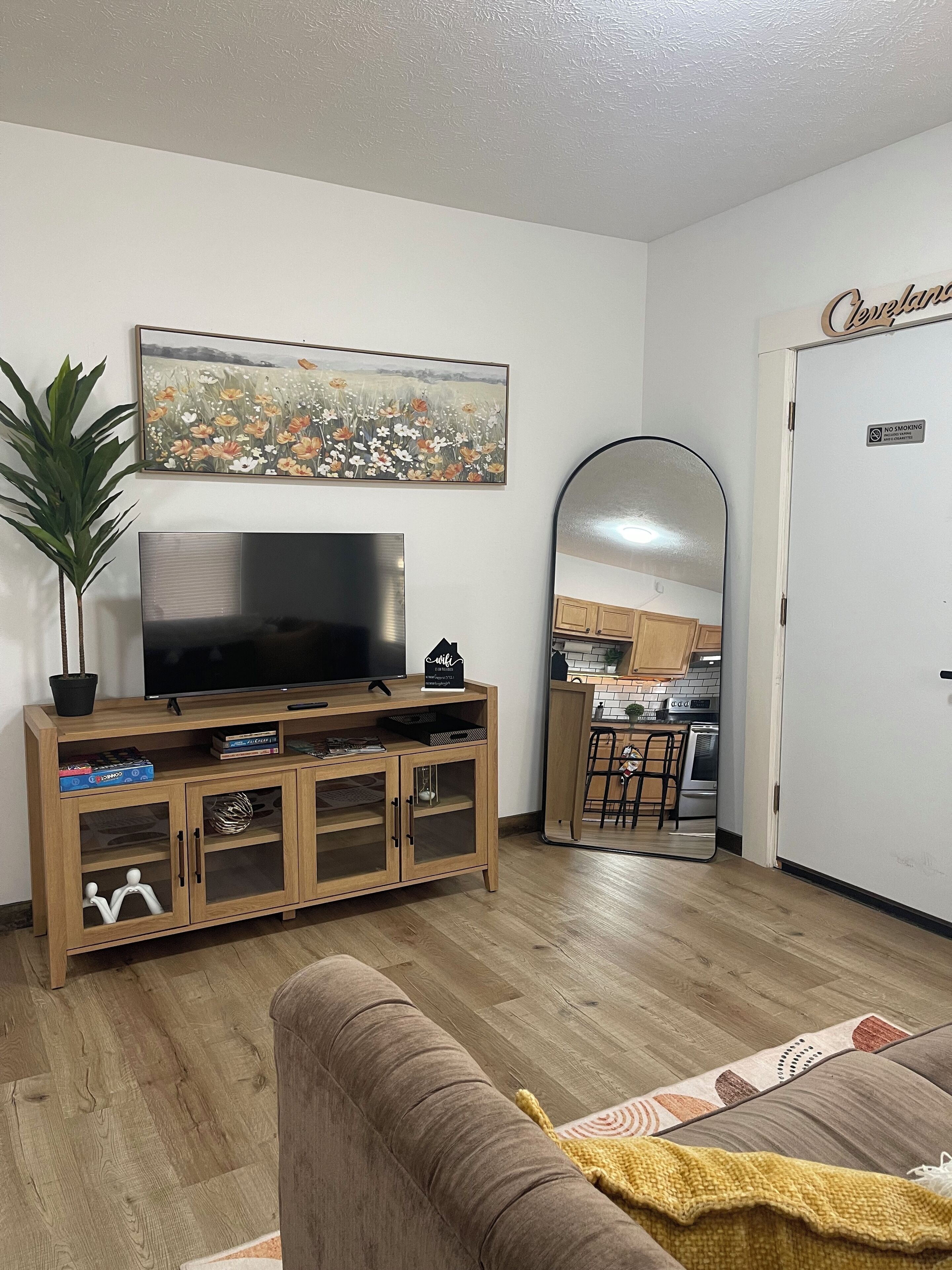 Ein Wohnzimmer mit Fernseher, Holz-Entertainment-Möbel und einer Topfpflanze.