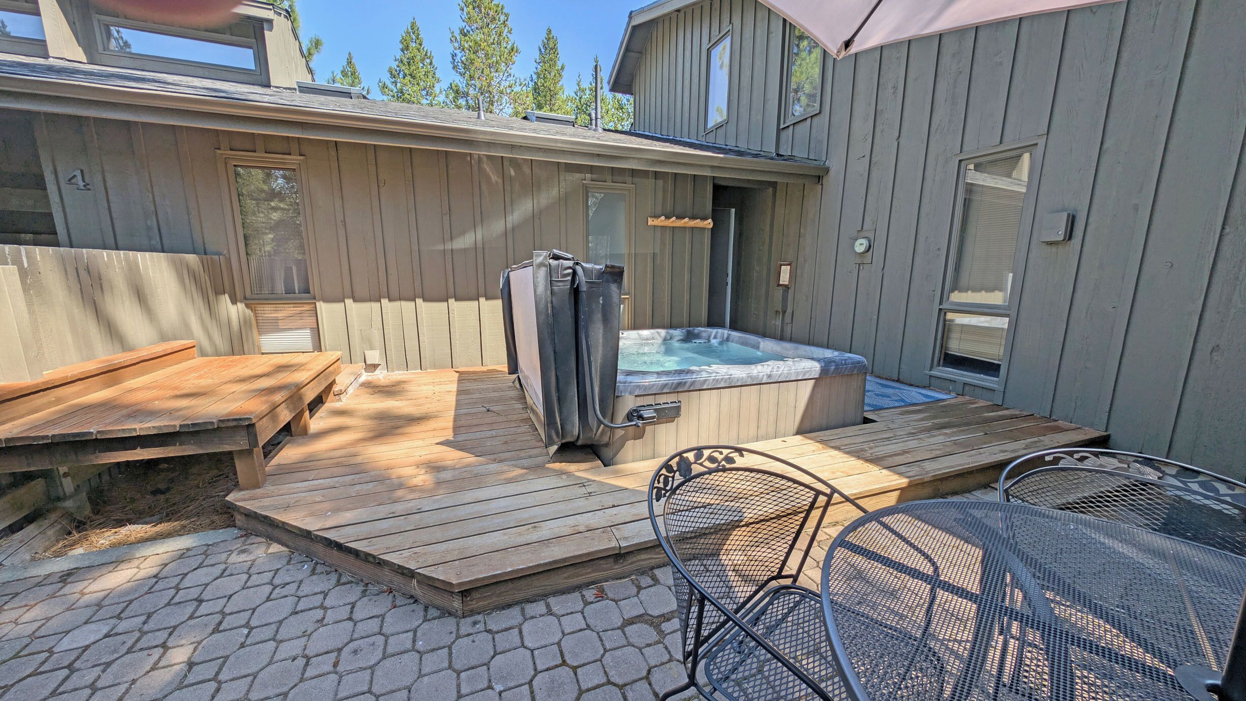 A backyard with a hot tub, wooden deck, and outdoor seating area.