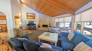 A cozy living room with a stone wall, a flat-screen TV, and a large window.