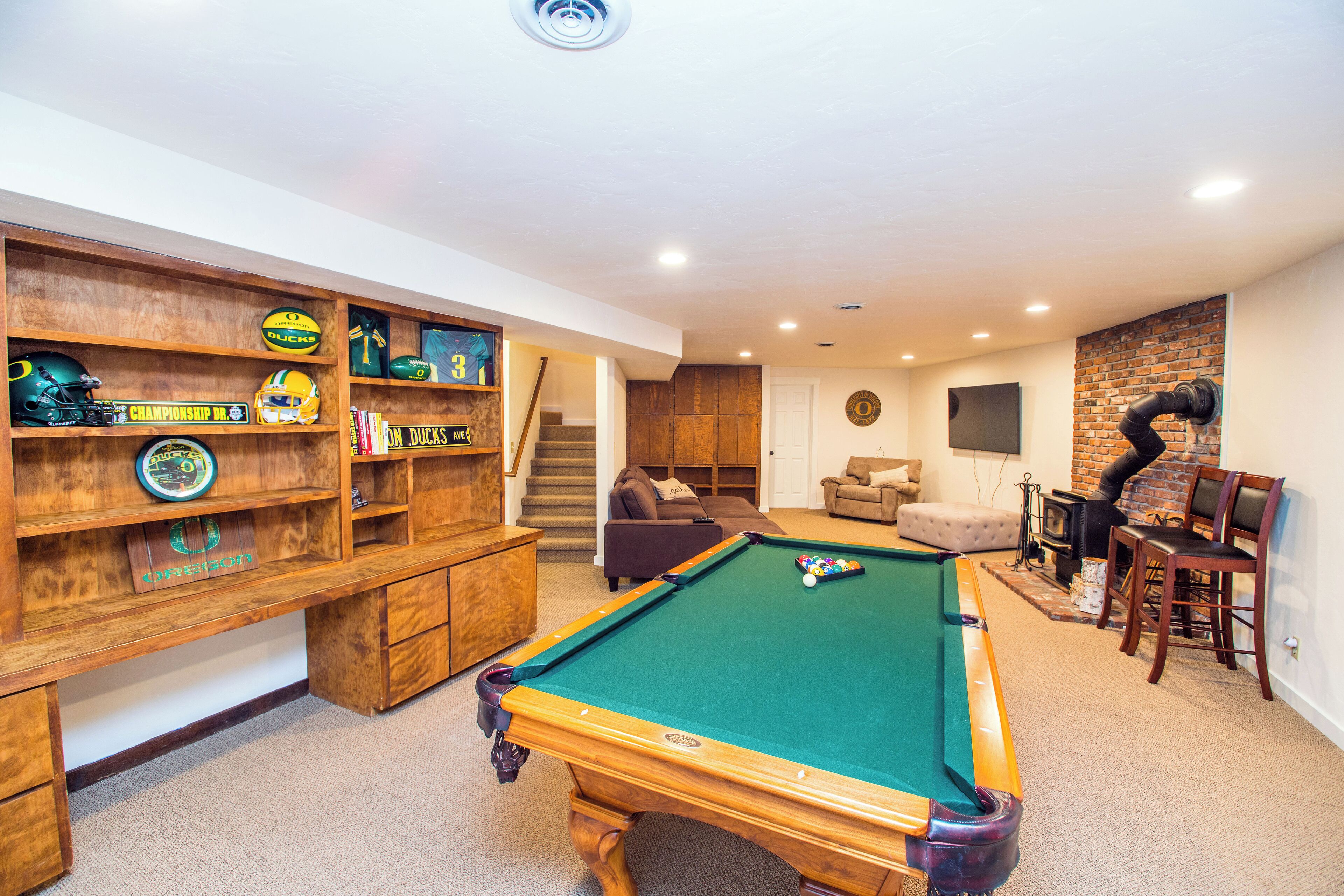 Een pooltafel in een ruimte met een houten wandplank waarop sportmemorabilia staan.