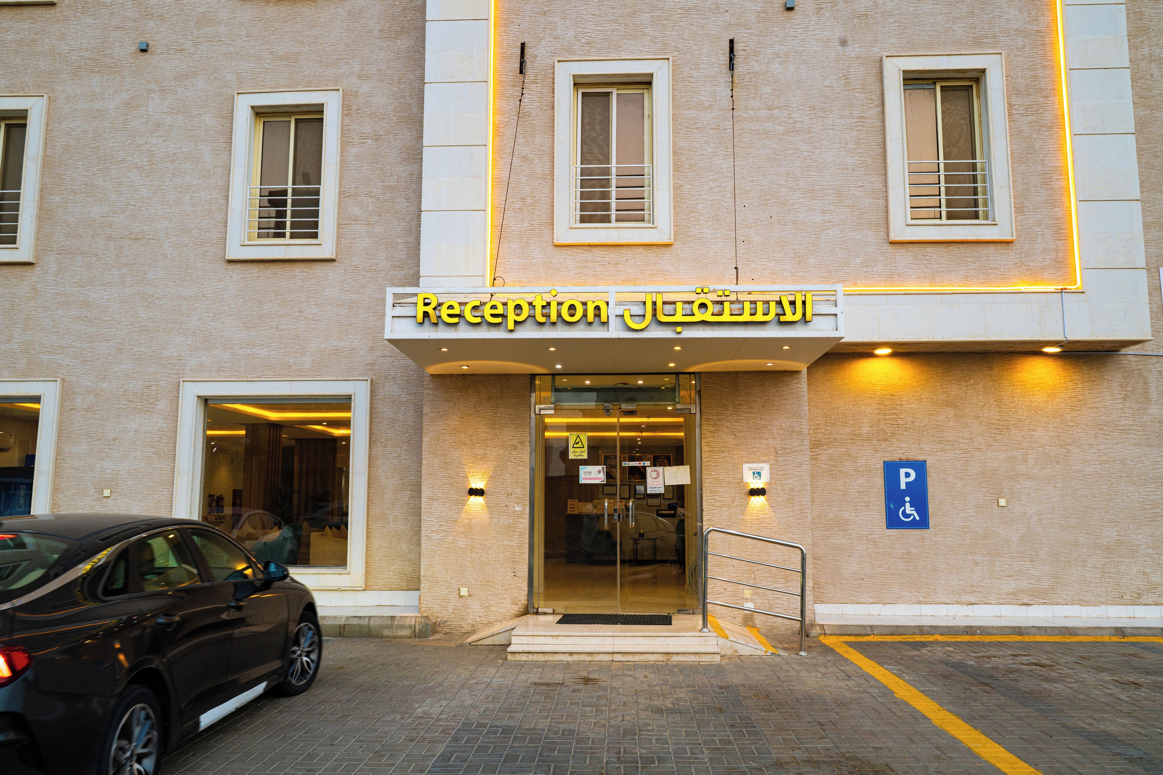 A building with a reception area, a parking sign, and a car parked in front.