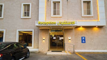 A building with a reception area, a parking sign, and a car parked in front.