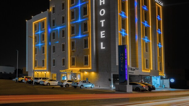 A multi-story hotel with illuminated signage and a modern facade. - Akarem Jazan Serviced Apartments (Jizan)