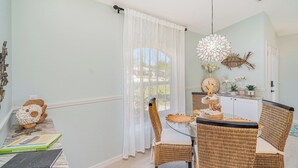 A dining area with wicker chairs, a round table, and a white tablecloth. - Sunset (Rotonda West)