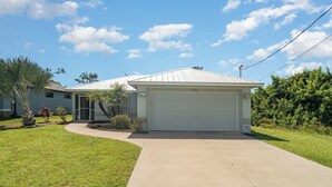 A single-story house with a garage, surrounded by a well-maintained lawn and a palm tree. - Sunset (Rotonda West)