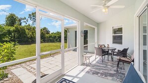A covered patio with a ceiling fan, a table with chairs, and a view of a grassy yard. - Sunset (Rotonda West)