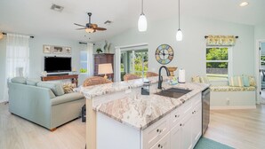 A spacious living area with a sofa, a TV, a dining table, and a kitchen island. - Sunset (Rotonda West)