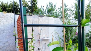 En have med et metal espalier, plantekasser og en flisevæg.