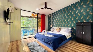 A bedroom with a bed, a wardrobe, a ceiling fan, a window with a view, and a balcony with chairs. - RKS RESORT KARJAT (Karjat)