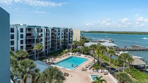 Un hotel con piscina, palmeras y vistas al agua.