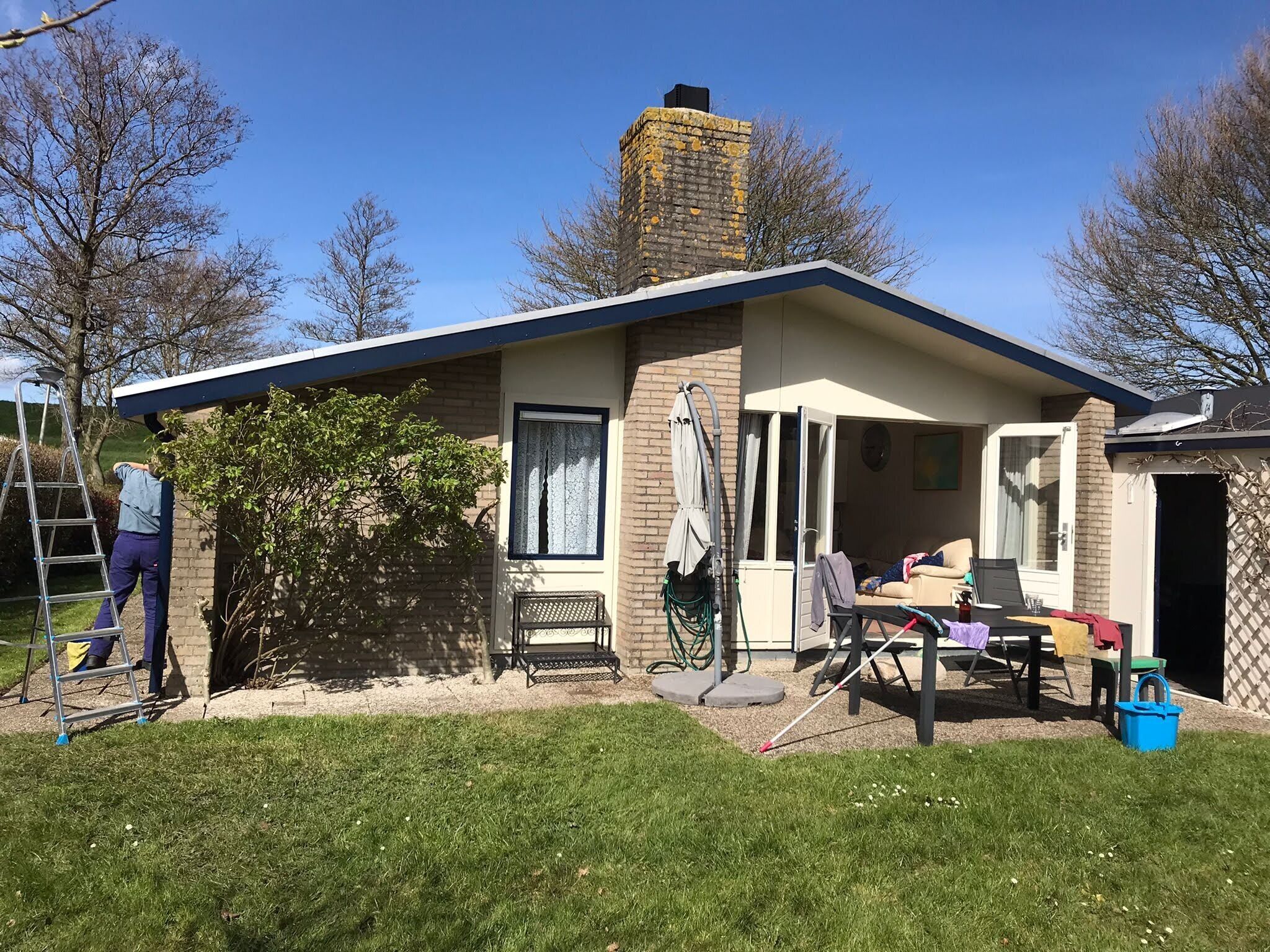Une maison de plain-pied avec un toit en pente, une cheminée en briques et un petit porche.