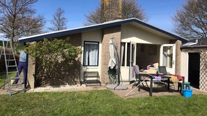 Una casa a un piano con tetto spiovente, un camino in mattoni e un piccolo portico.