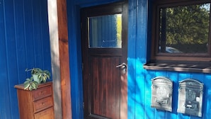 A wooden door with a window above it, a mailbox, and a small wooden cabinet with plants.