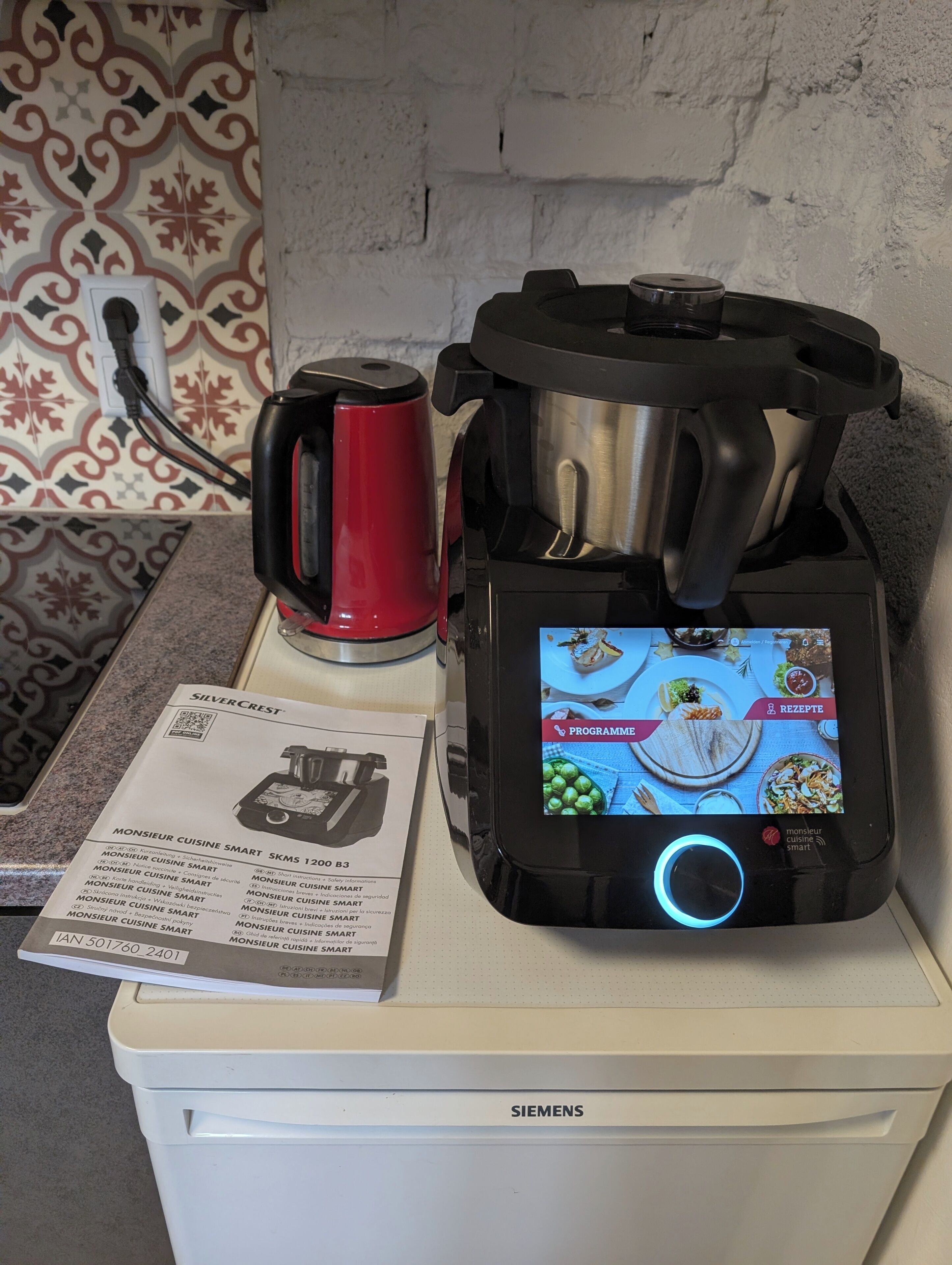 Eine Küche mit einem Siemens-Gerät, einem roten Wasserkocher und einem digitalen Rezeptdisplay.