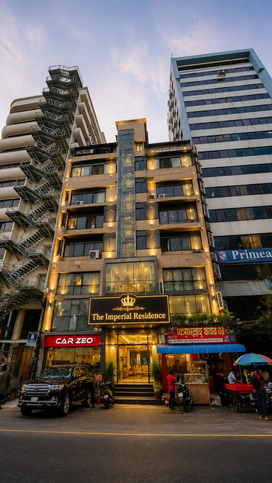 A multi-story hotel with a prominent entrance, a sign for 'The Imperial Residence,' and a visible storefront with a 'CAR ZEO' sign.