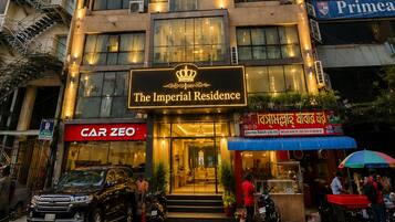 A multi-story hotel with a prominent entrance, a sign for 'The Imperial Residence,' and a visible storefront with a 'CAR ZEO' sign.