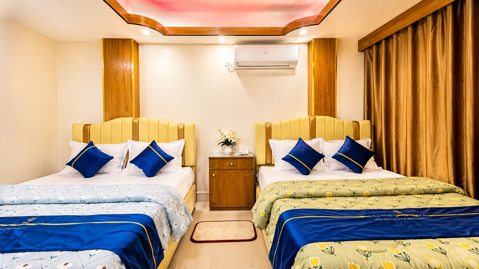 A hotel room with two beds, a nightstand, and an air conditioning unit.