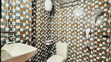 Une salle de bain avec un mur carrelé, des toilettes, un lavabo et une douche.