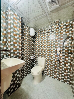 A bathroom with a tiled wall, a toilet, a sink, and a shower. - The Imperial Residence Banani (Dhaka)