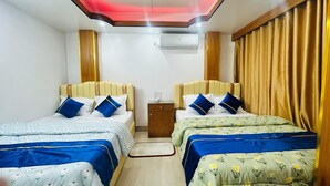 A hotel room with two beds, each with a headboard, a bedside table, and an air conditioning unit on the wall. - The Imperial Residence Banani (Dhaka)