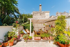 Un jardin sur le toit, agrémenté de plantes en pot, un espace repas et une cheminée en pierre.