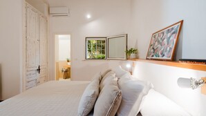 A bedroom with a bed, pillows, a bedside table, a mirror, and a window with a view of greenery. - Terrace Le Colonne - Lecce Selection (Lecce)