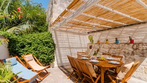 A private terrace with a wooden table set for dining, surrounded by wicker chairs, and a shaded area with a woven roof. - Terrace Le Colonne - Lecce Selection (Lecce)