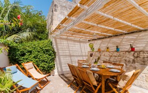 A private terrace with a wooden table set for dining, surrounded by wicker chairs, and a shaded area with a woven roof. - Terrace Le Colonne - Lecce Selection (Lecce)