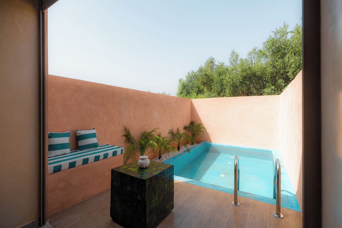 Un espace piscine extérieur moderne, doté d’un coin salon et d’une petite table.