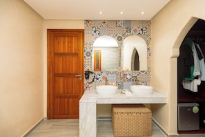 A bathroom with a wooden door, two sinks, a mirror, and a tiled backsplash. - Villa Stevana (Oulad Hassoune)