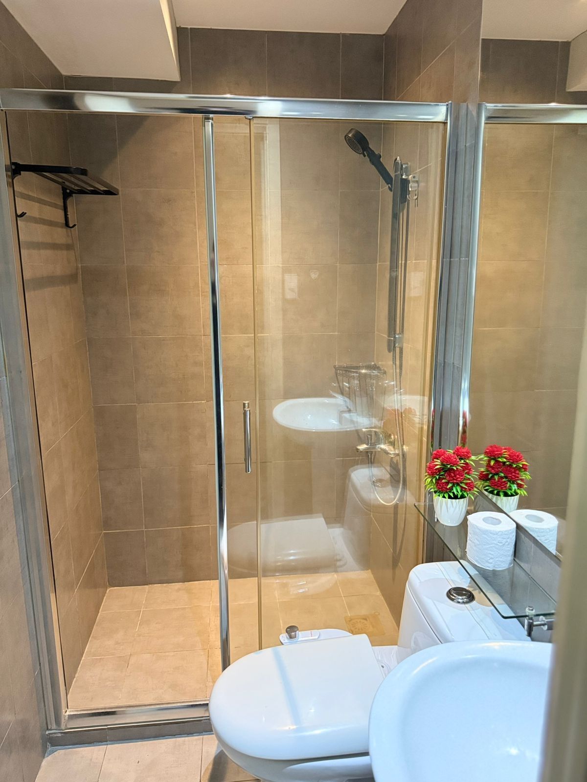 Un baño moderno con ducha de vidrio, inodoro blanco y lavamanos.