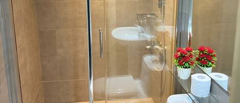 Un baño moderno con ducha de vidrio, inodoro blanco y lavamanos.