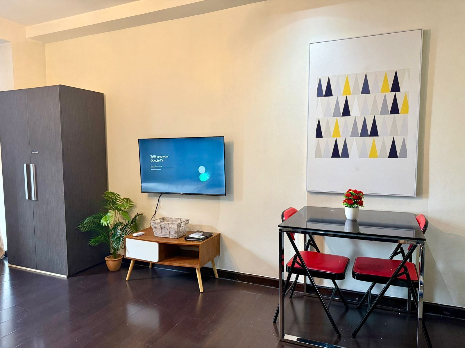Una sala de estar moderna con una televisión de pantalla plana, una mesa de centro de madera, una silla roja y una planta en maceta.