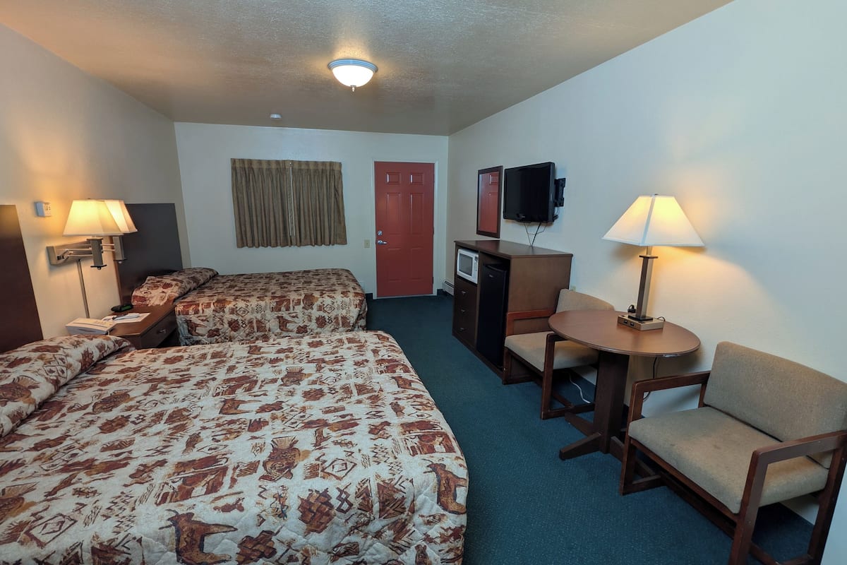 Une chambre d’hôtel avec deux lits, un bureau, une chaise, une télévision et un four à micro-ondes.