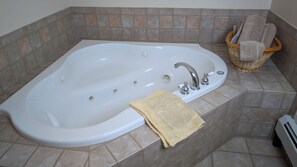 A bathroom with a freestanding bathtub, a wicker basket with towels, and a towel on the floor.