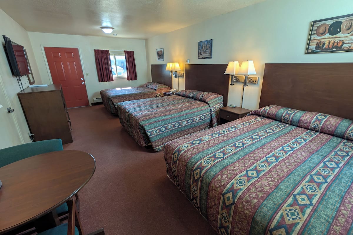 Une chambre d’hôtel avec deux lits, un bureau, une chaise, une télévision et une porte.