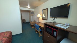 Une chambre d’hôtel équipée d’un bureau, d’une chaise, d’un lit, d’une télévision, d’une lampe et d’un téléphone.