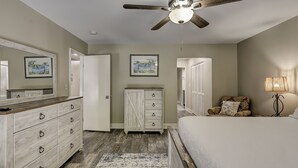 A bedroom with a ceiling fan, a dresser, a cabinet, a bed, and a nightstand.