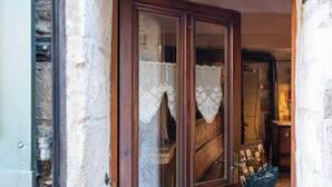 Une porte en bois avec un paillasson en dentelle, un mur en pierre et un sol carrelé.