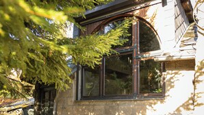 Un bâtiment rustique avec une façade en pierre, une grande fenêtre en arc de cercle et une porte en bois.