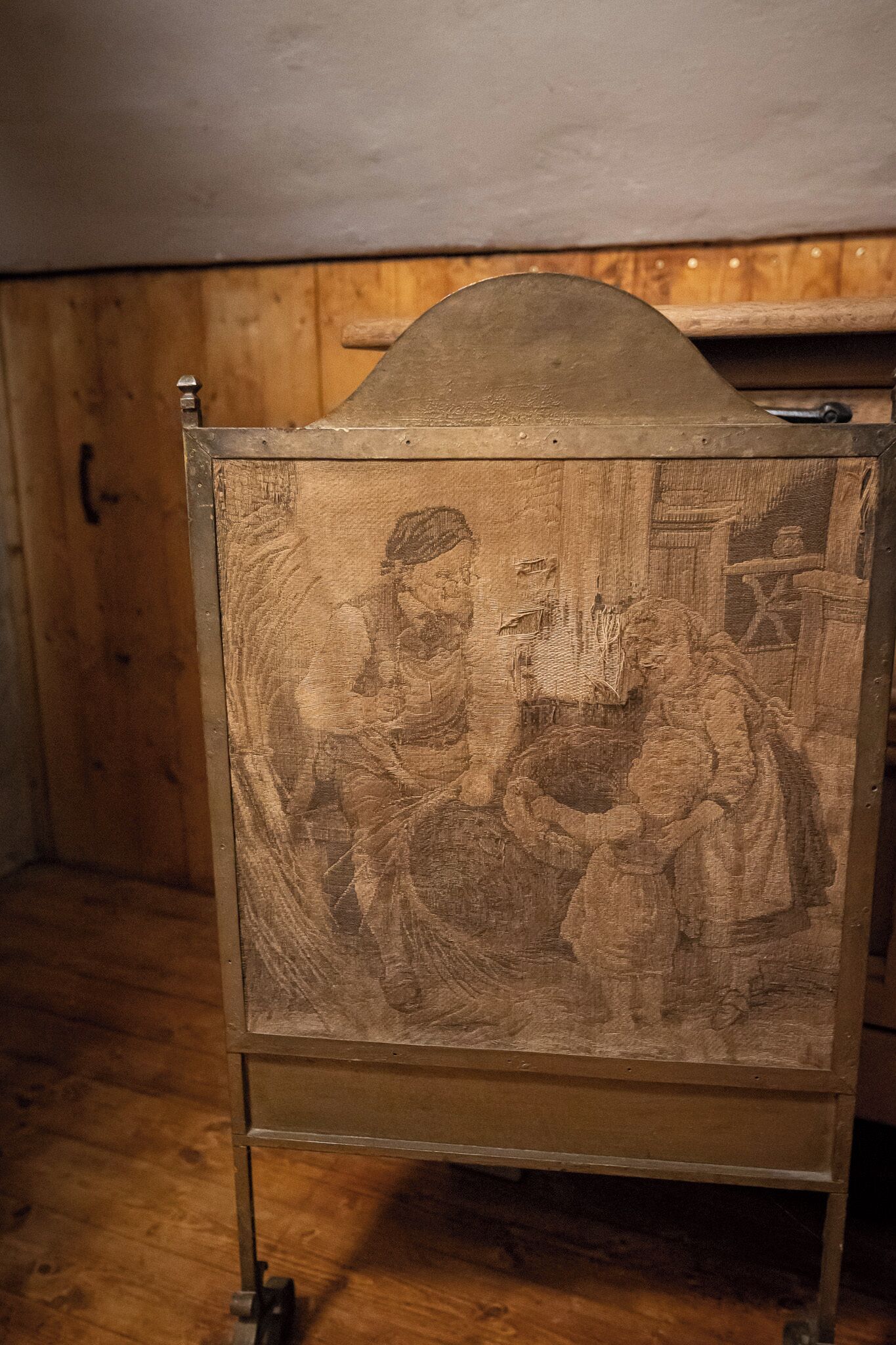 A wooden cabinet with a metal top and a detailed carved scene.