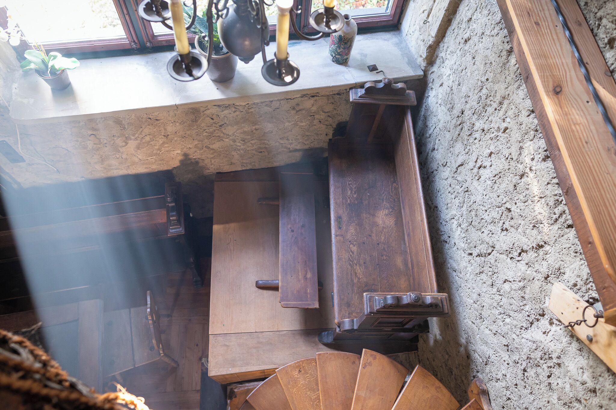 A rustic wooden bench with a stone wall and a window with candles.