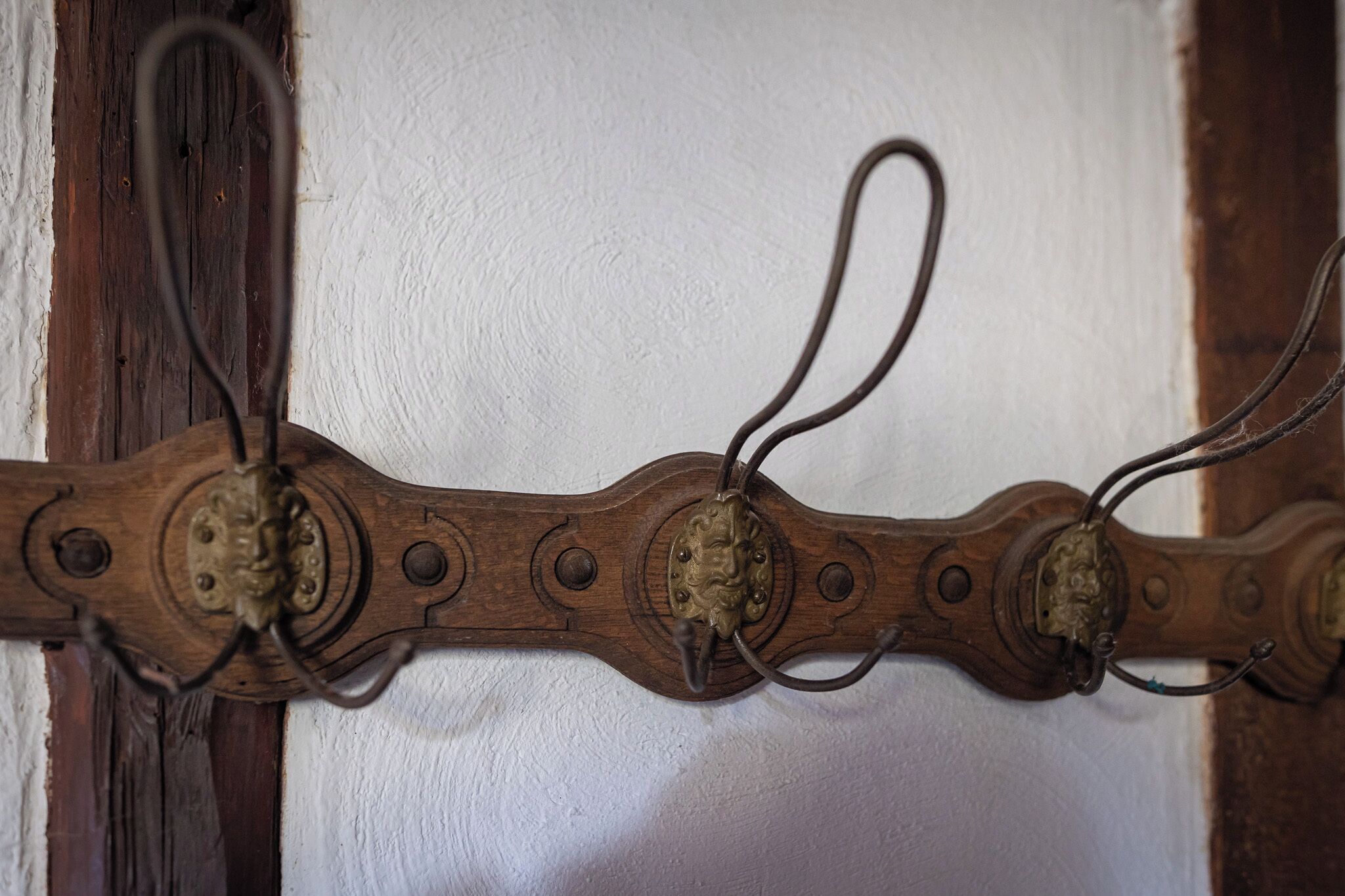 Un gancio di legno da parete con anelli metallici ed elementi decorativi.