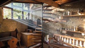 Une cuisine rustique, avec des meubles en bois, un escalier en colimaçon et des étagères remplies d’ustensiles de cuisine.