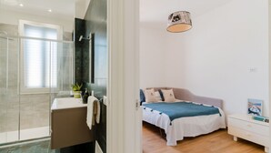 Een moderne badkamer met een douchecabine van glas, een witte wastafel en een spiegel.